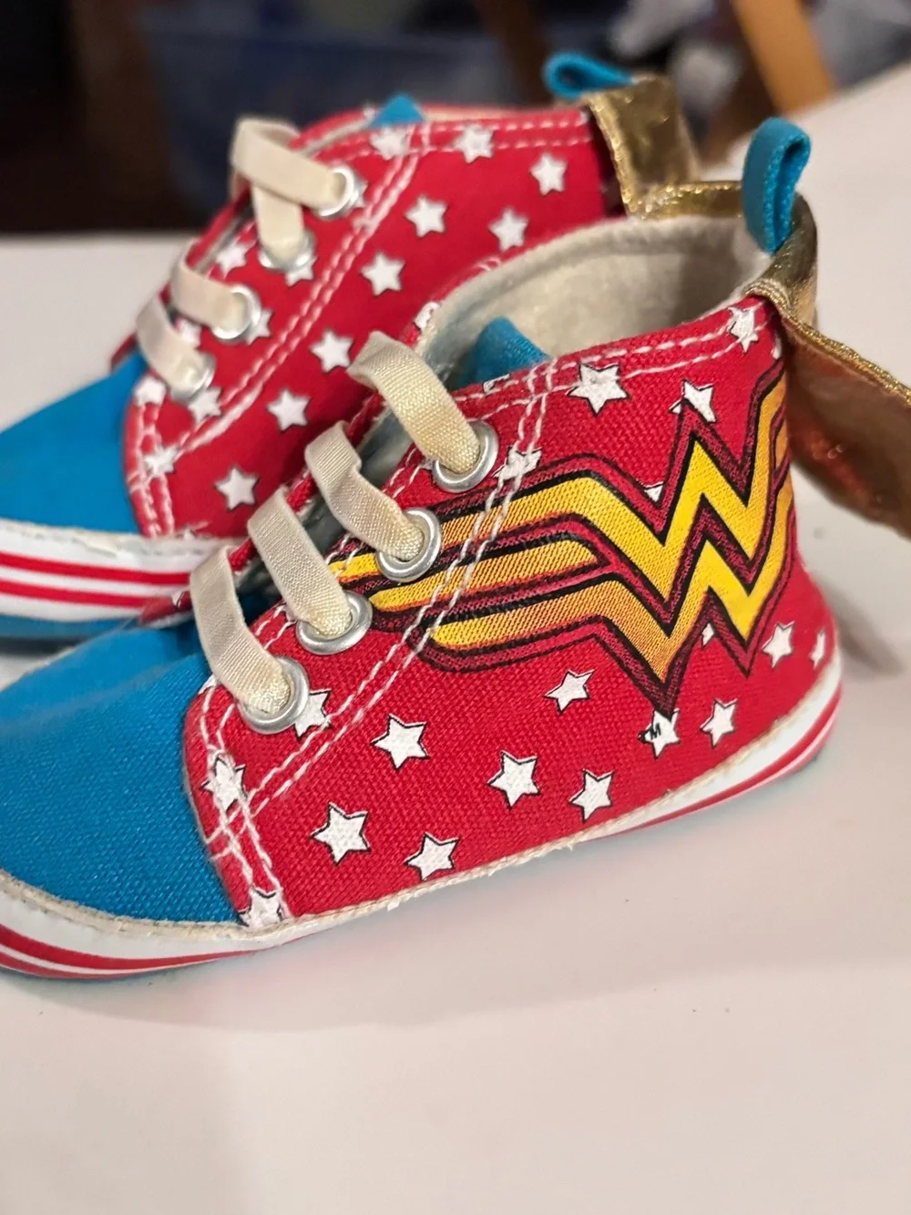 DC Comics baby sneaker with Wonder Woman logo. Red canvas with Gold Capes.